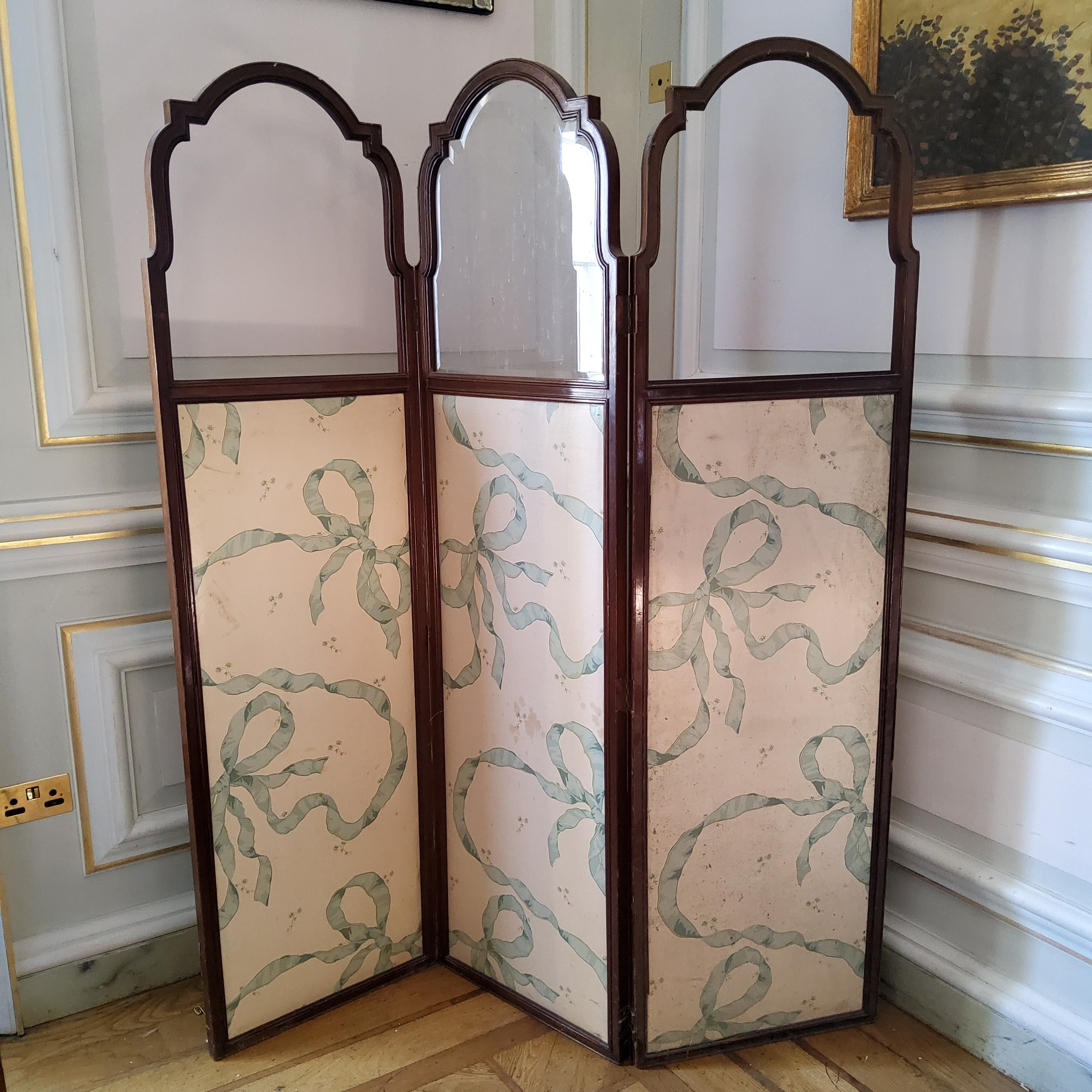 An Edwardian mahogany threefold modesty screen, bold ribbon tied upholstered panels standing c.