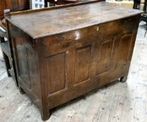 An 18th century vernacular oak Welsh coffer, the cover with early wooden hinges, brass lock above