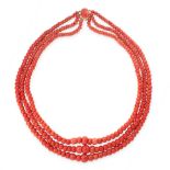 A CORAL BEAD NECKLACE in yellow gold, comprising three rows of graduated polished coral beads