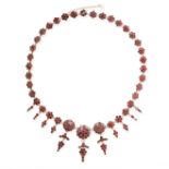 AN ANTIQUE GARNET NECKLACE set with graduated floral clusters of flat cut garnets, suspending