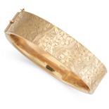 A VINTAGE GOLD BANGLE in 9ct yellow gold, the hinged body decorated with engraved foliate designs,