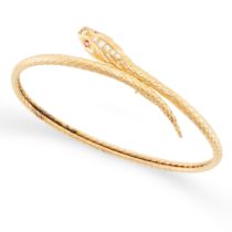 A RUBY AND DIAMOND SNAKE BANGLE in yellow gold, designed as a coiled snake, the head set with