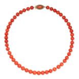 A CORAL BEAD NECKLACE comprising a single row of polished red coral beads, the clasp set with a