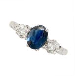 A SAPPHIRE AND DIAMOND THREE STONE RING set with an oval cut sapphire between two round brilliant
