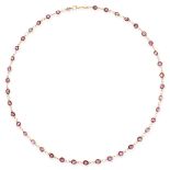 A GARNET CHAIN NECKLACE in yellow gold, set with a row of round cut garnets on a chain necklace,