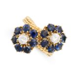 A SAPPHIRE AND DIAMOND CROSSOVER RING set with two clusters of round brilliant cut diamonds and