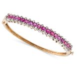 A RUBY AND DIAMOND BANGLE in 14ct yellow and white gold, set with a row of round cut rubies all
