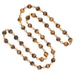 A TIGER'S EYE AND GOLD BEAD NECKLACE in yellow gold, comprising a single row of alternating polished