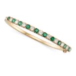 AN EMERALD AND DIAMOND BANGLE in yellow gold, set with a row of alternating round cut emeralds and