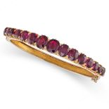 AN ANTIQUE UNHEATED RUBY BANGLE in yellow gold, set with a single row of graduated cushion cut