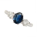 A SAPPHIRE AND DIAMOND THREE STONE RING set with an oval cut sapphire between two round brilliant...