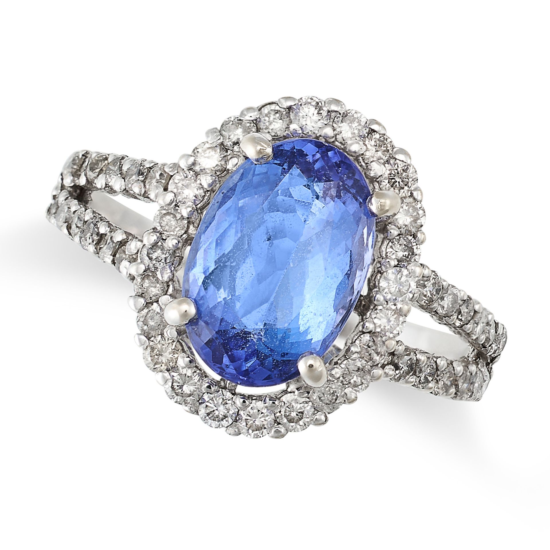 A TANZANITE AND DIAMOND CLUSTER RING in white gold, set with an oval cut tanzanite of approximate...