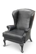 A CONTEMPORARY BLACK LEATHER UPHOLSTERED WING-BACK ARMCHAIR