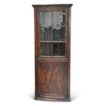 A GEORGE III ELM BOW-FRONT FLOOR-STANDING CORNER CUPBOARD