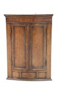 A GEORGE III-STYLE OAK BOW-FRONT HANGING CORNER CUPBOARD