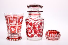 A MID-19TH CENTURY BOHEMIAN RED FLASH CUT GLASS BEAKER, JAR AND COVER, AND PIN BOWL