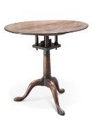 A GEORGE III MAHOGANY TILT-TOP TRIPOD TABLE, the circular top raised on a gun barrel stem,