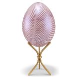 A DAUM GLASS EGG, of feather design, signed and indistinctly numbered, on a brass stand. 19cm high