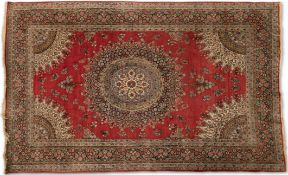 A PERSIAN RUG, hand-knotted, the deep red field with a highly decorative cream and blue circular