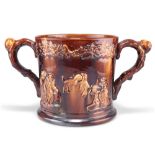 A LARGE 19TH CENTURY STAFFORDSHIRE TREACLE GLAZE LOVING CUP, moulded decoration depicting tavern