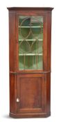 A GEORGE III MAHOGANY FLOOR-STANDING CORNER CABINET, the glazed door with moulded bars forming an