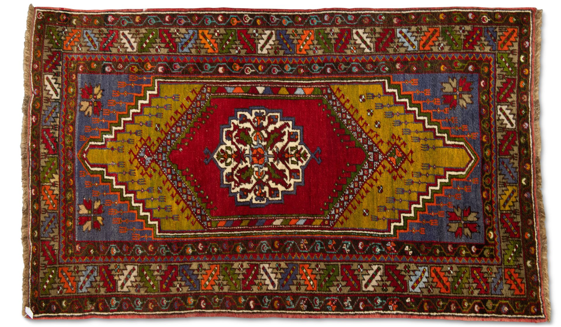 A TURKISH RUG, hand-knotted and multicoloured, the dark red lozenge enclosing a cream medallion,
