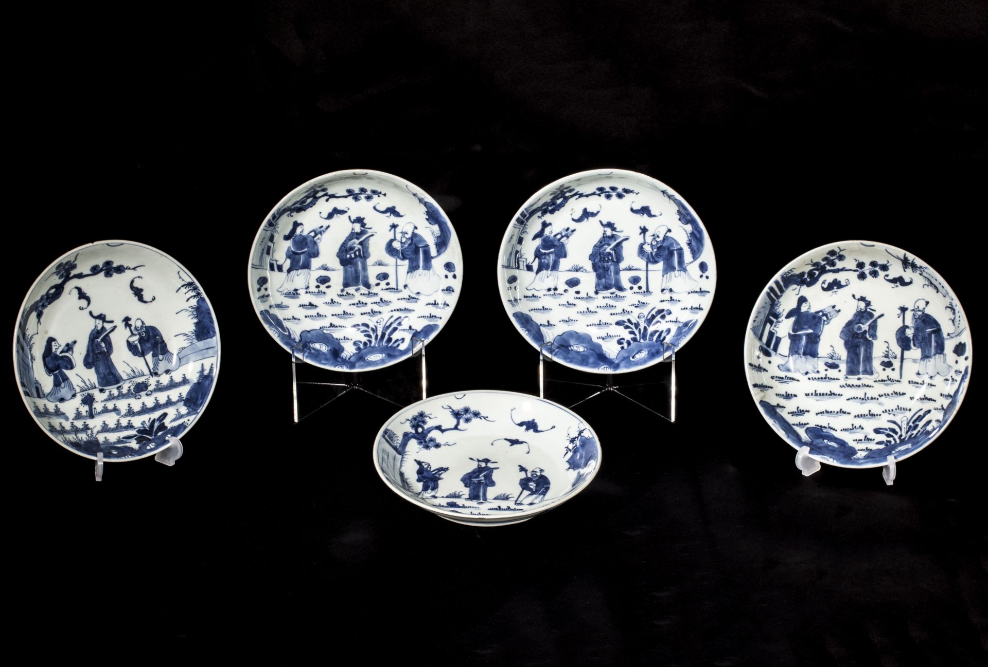 Suite de cinq assiettes en porcelaine blanche décorée en bleu sous couverte de trois personnages