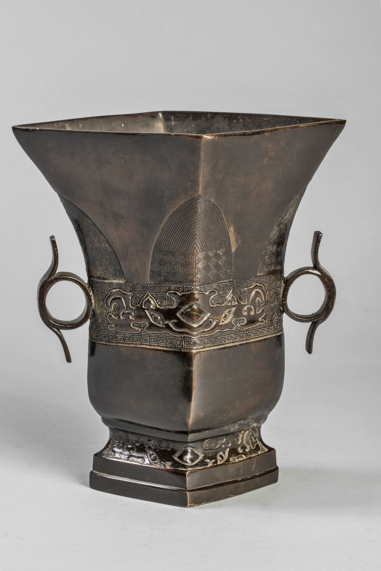 Vase en forme d'urne quadrangulaire moulé d'un décor archaïsant serti de deux anses anneaux Bronze