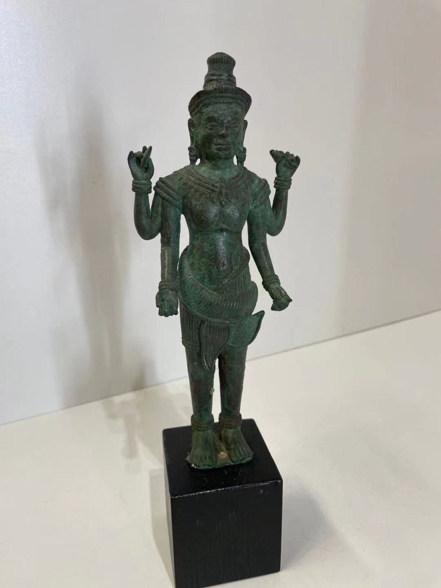 Vishnu debout dans une posture hiératique , sous une forme à quatre bras, tenant de ses deux mains