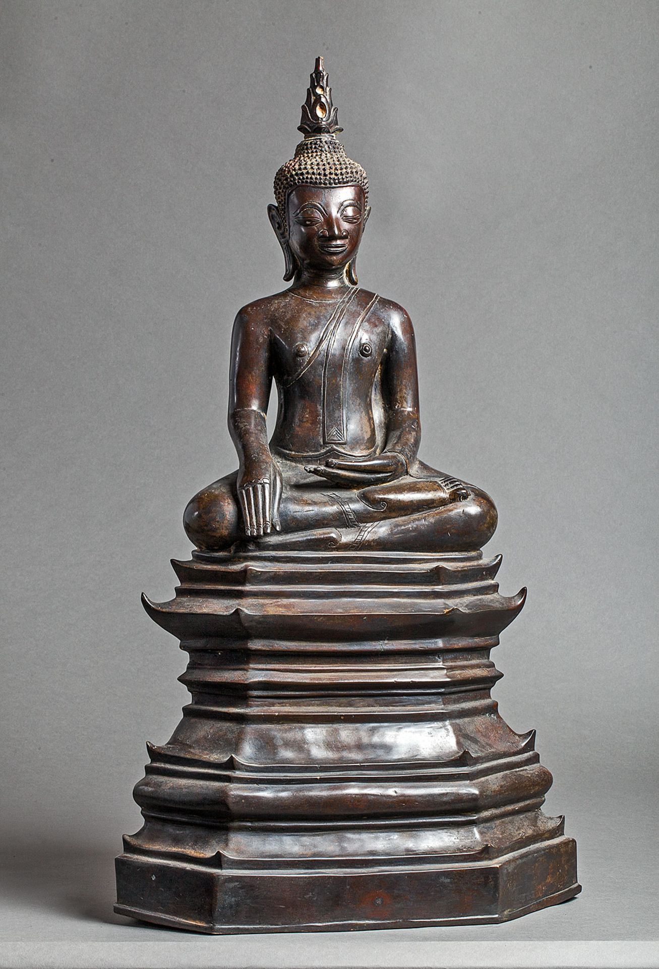 Buddha Maravijaya assis sur un haut socle étagé, les jambes en virasana et la main droite en