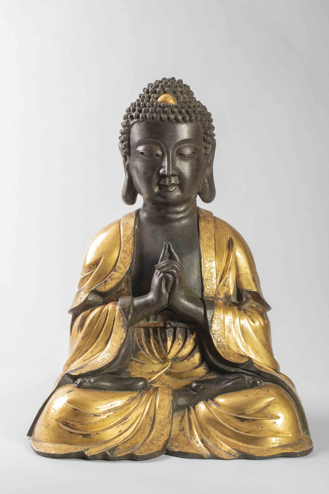 Buddha Amida ainsi en méditation, vêtue d’une robe monastique plissé lui couvrant les deux