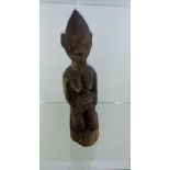 Carved African 20th century figurine kneeling and holding a face