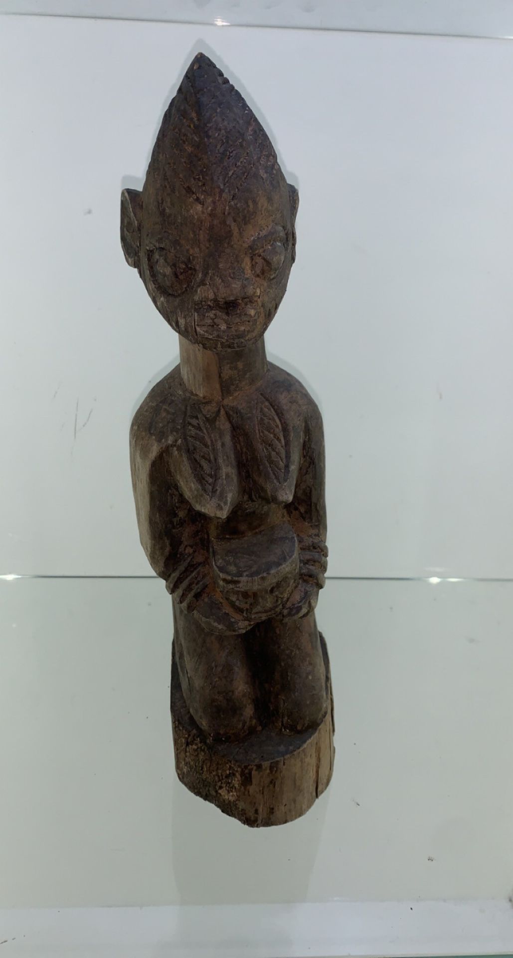 Carved African 20th century figurine kneeling and holding a face