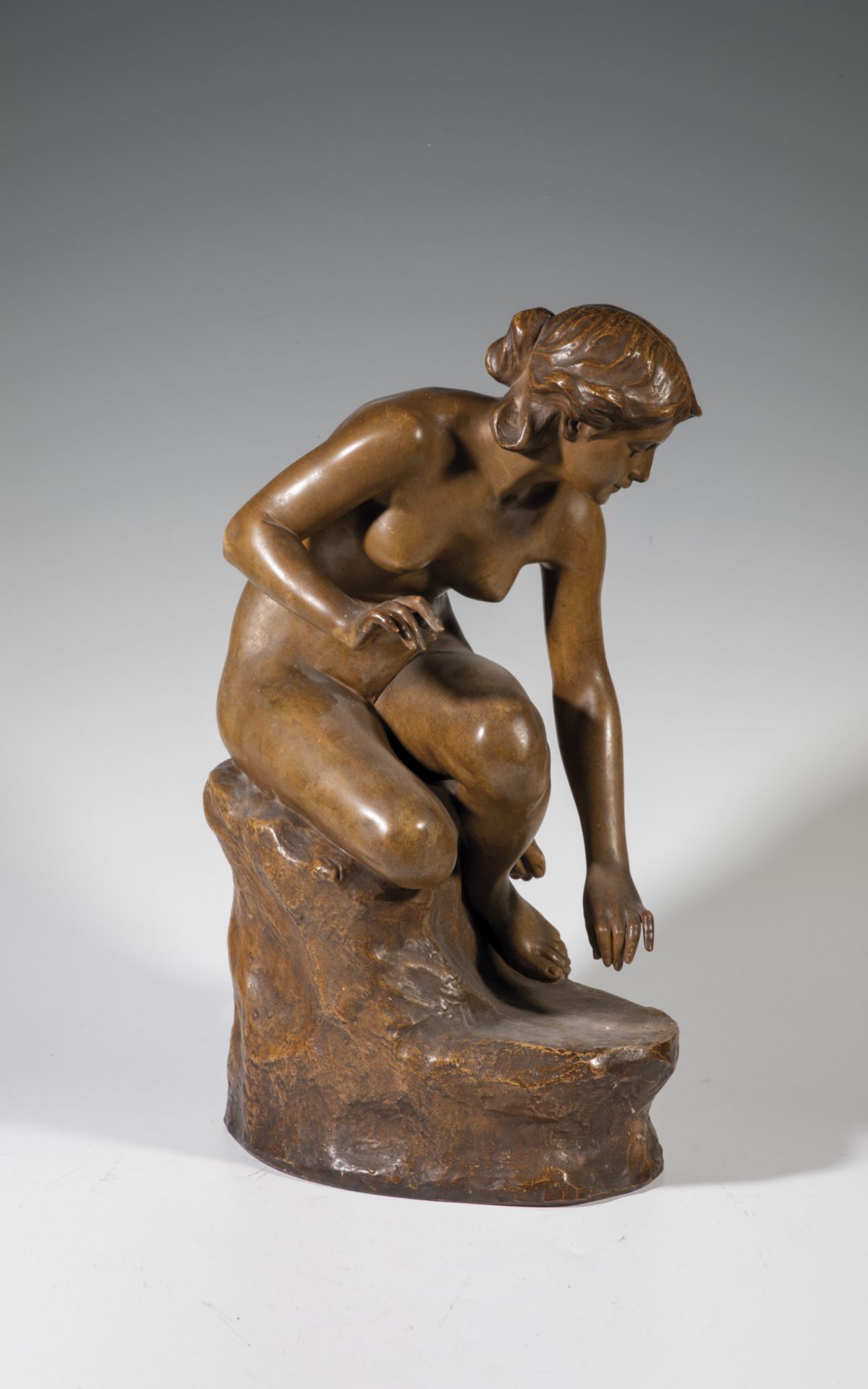 Sitting bending female nude on rock pedestal