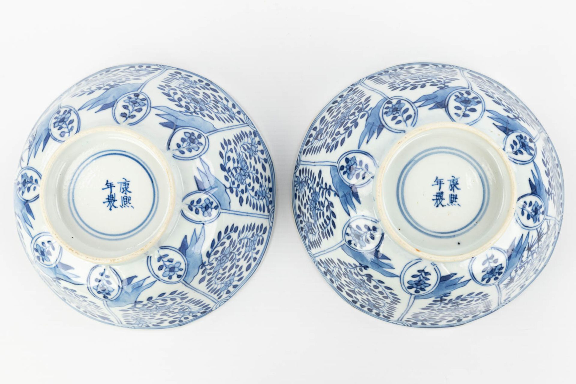 A pair of Chinese bowls made of porcelain with blue-white flower decor and marked Kangxi. (H:7,2cm) - Image 10 of 13