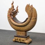 A Xylophone made of sculptured wood in the shape of a dragon and standing on a stone base. Indonesia