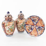 A pair of Japanese baluster vases with lid and a plate, made of hand-painted porcelain. (23 x 20 cm)