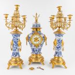 A three-piece mantle clock with candelabra made of Delft's porcelain mounted with bronze. (17 x 23 x
