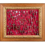 A frame filled with small crucifixes and scapulars (68 x 58cm)