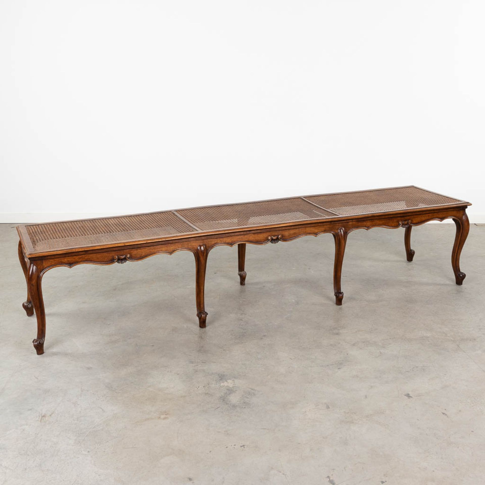 A long bench made of sculptured wood in Louis XV style finished with caning. (L:48 x W:218 x H:44 c