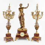 A three-piece mantle garniture clock and candelabra, polished bronze and red marble. 19th century.