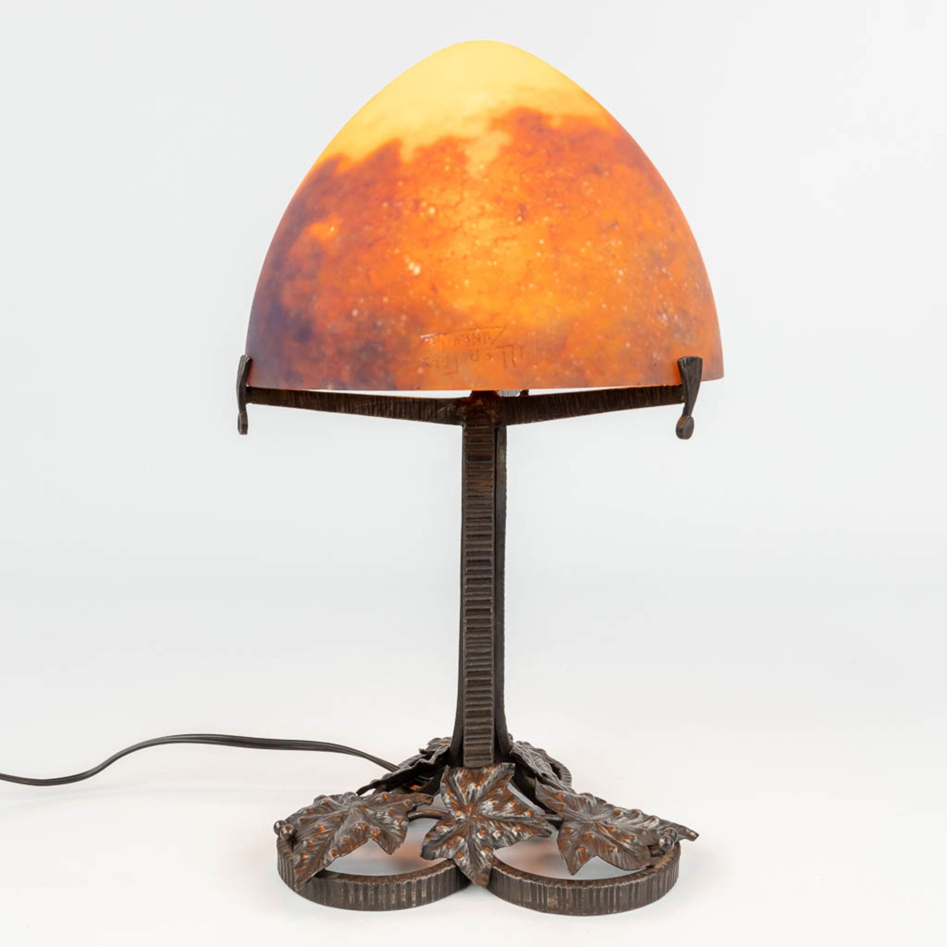 A wrought iron table lamp with pate de verre glass lampshade marked Muller Frres LunŽville. (H:39