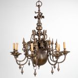 A large Flemish chandelier made of bronze, decorated with a figurine riding a mythological creature.
