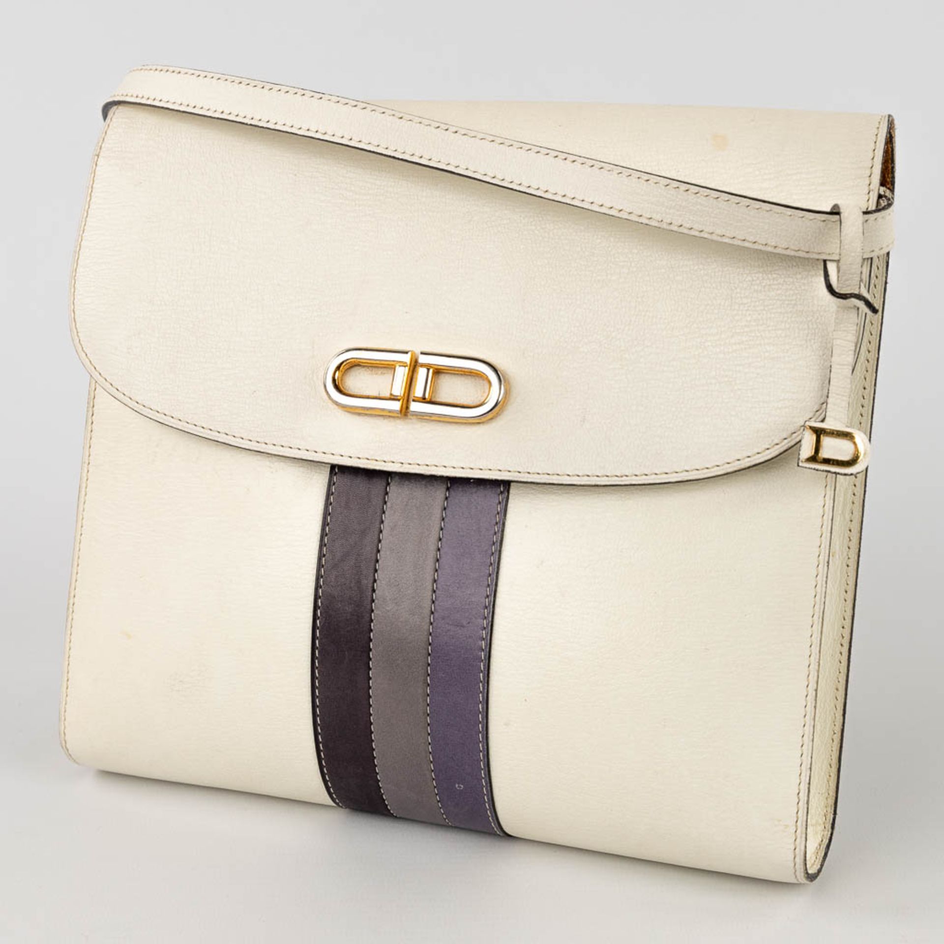 Delvaux, a handbag made of white leather decorated with colored stripes, and gold-plated hardware. (