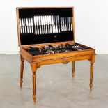 Christofle 'Berain Marot - Coquille', a 128-piece silver-plated cutlery set in a wood storage table.