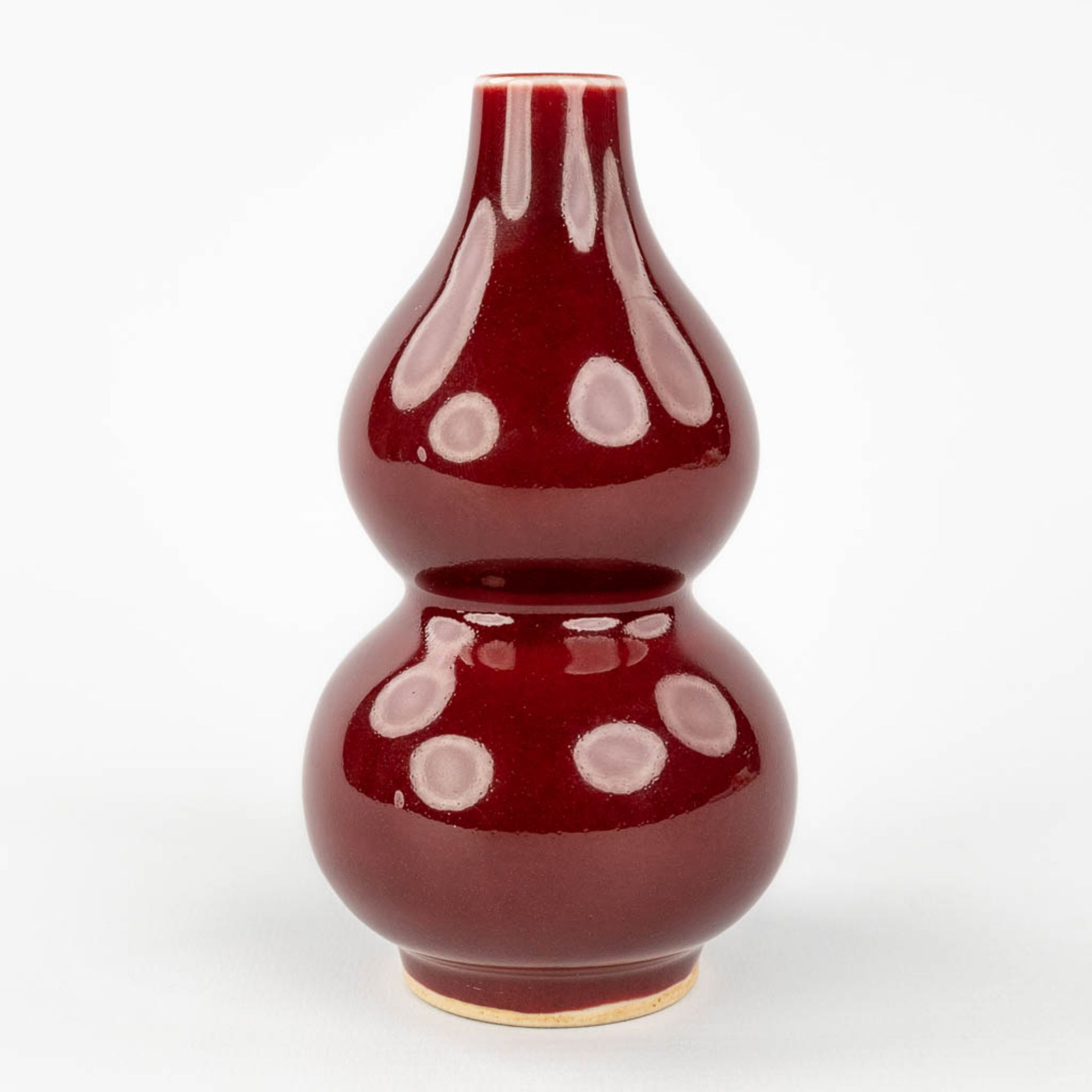 A Chinese double gourd vase, Sang De Boeuf glaze, 19th/20th century. (H: 13 x D: 7,5 cm)