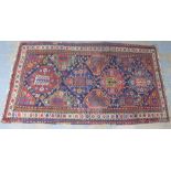 Kazak type rug, red and indigo field with geometric motifs and flowerhead border, 234 x 135cm (a/f)