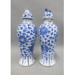 Pair of Chinese blue and white high shouldered baluster vases, covers with dog finials, painted