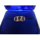 Vintage three stone amethyst dress ring, set to a scrolling yellow metal band, UK ring size K