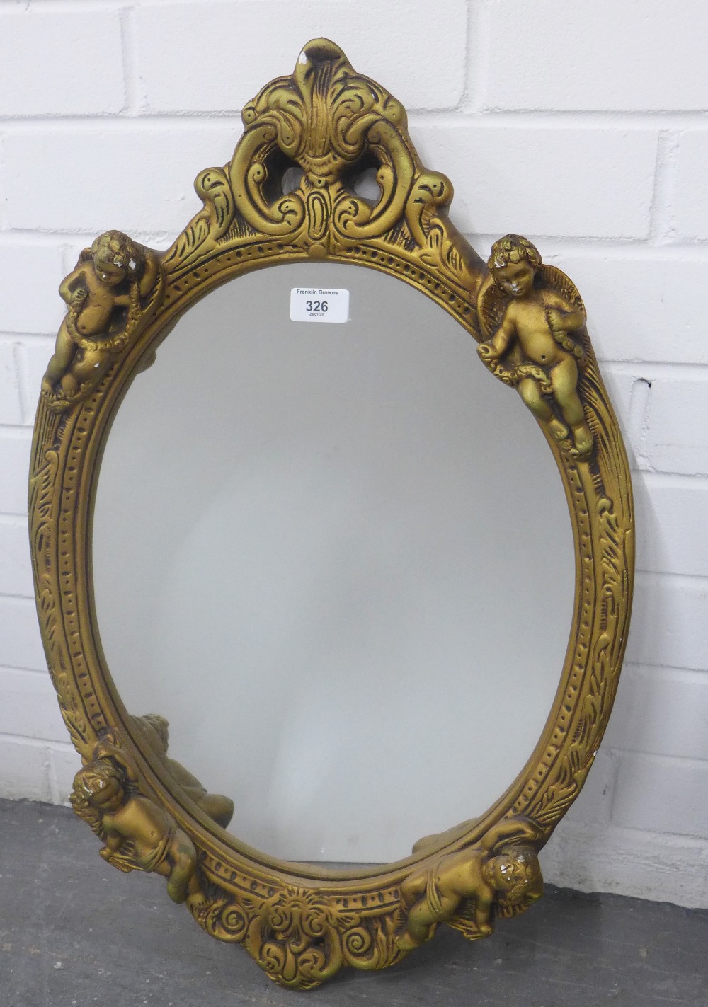 Faux giltwood cherub wall mirror with an oval plate, size overall 65 x 42cm